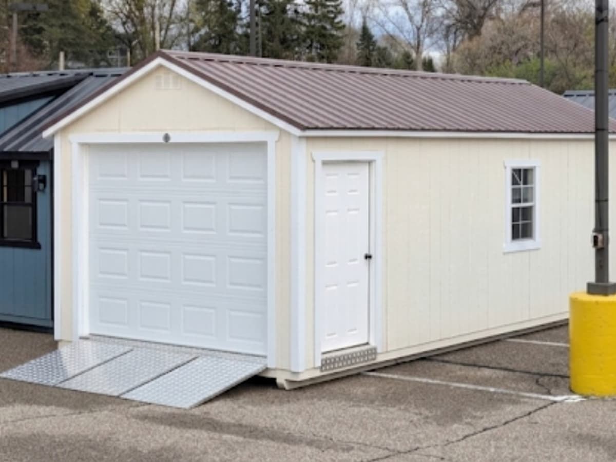 Cream Gable Garage with paneled overhead door, side entry door, and side window