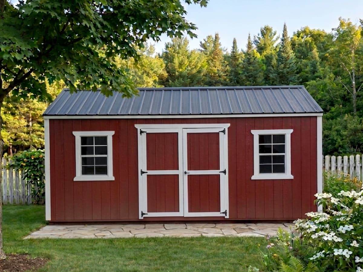 Red Classic shed with white trim, windows, and black metal roof on a flagstone pad