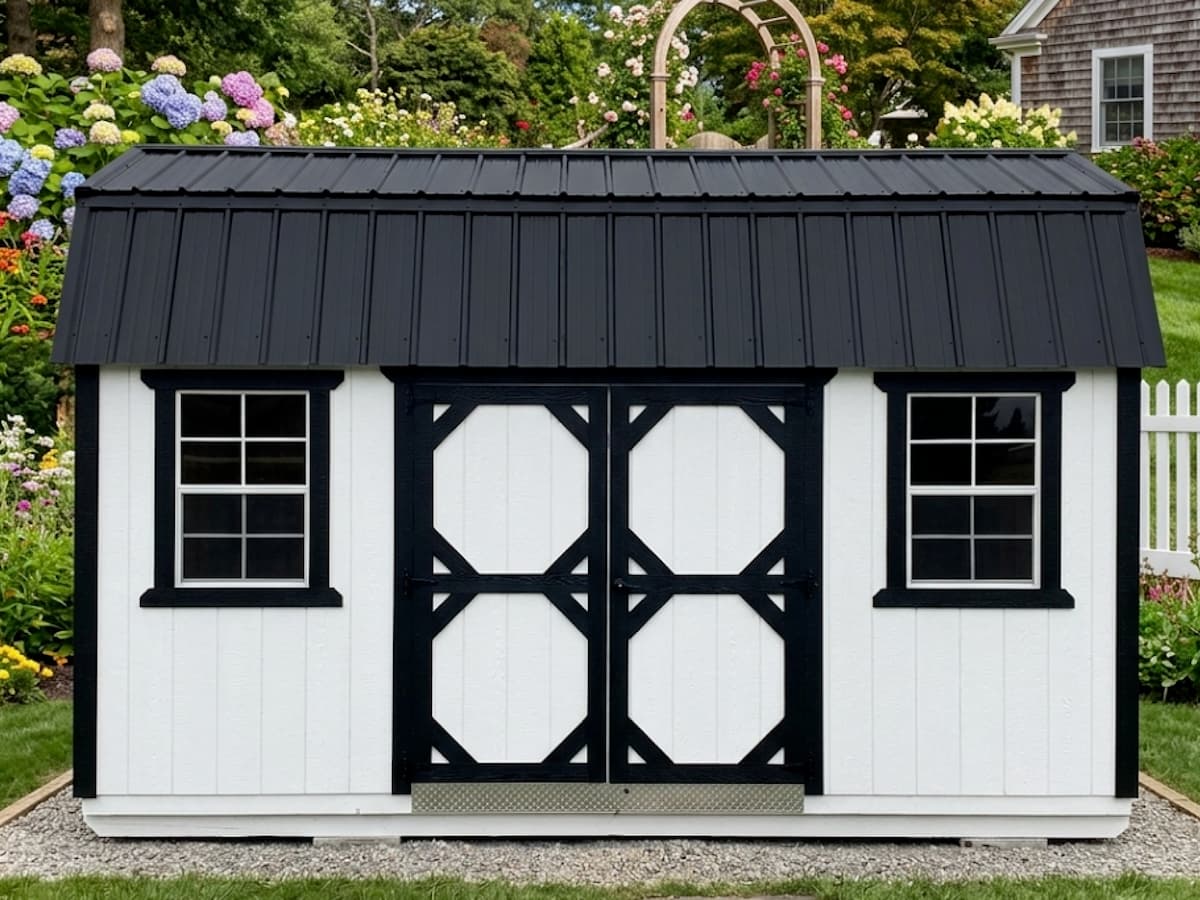 White Lofted Barn with black trim and octagon-pattern double barn doors in a garden