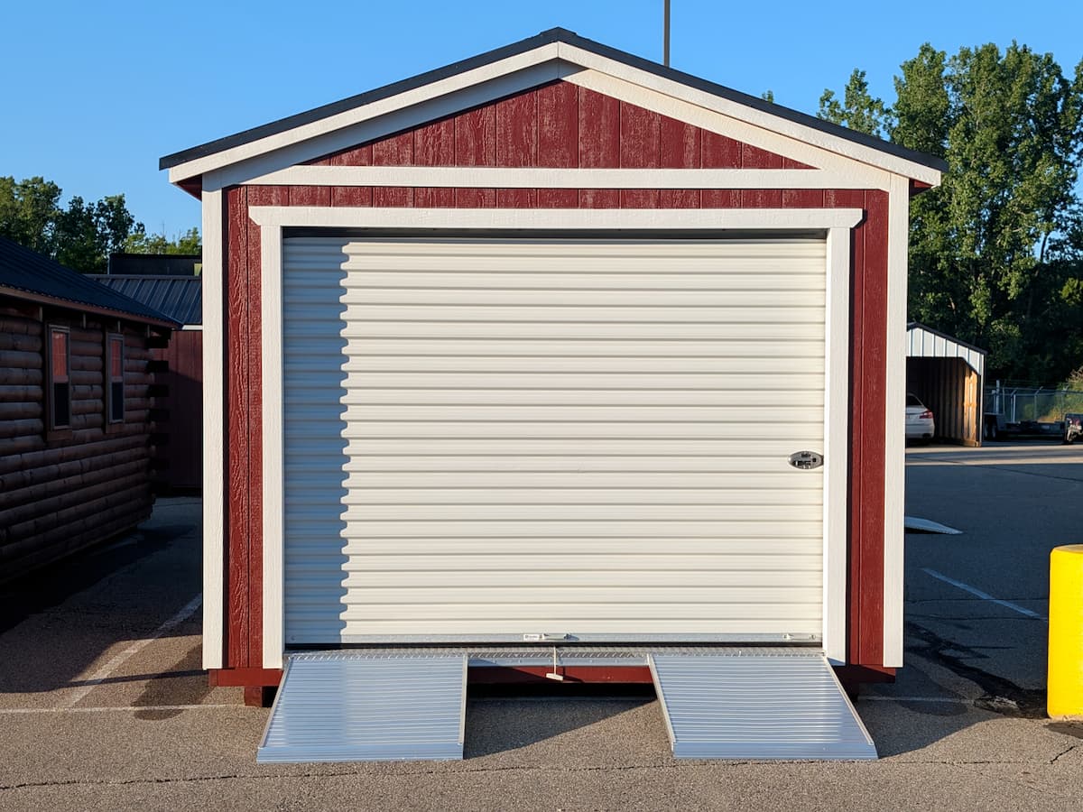 Red Gable Garage with white roll-up door and aluminum loading ramps