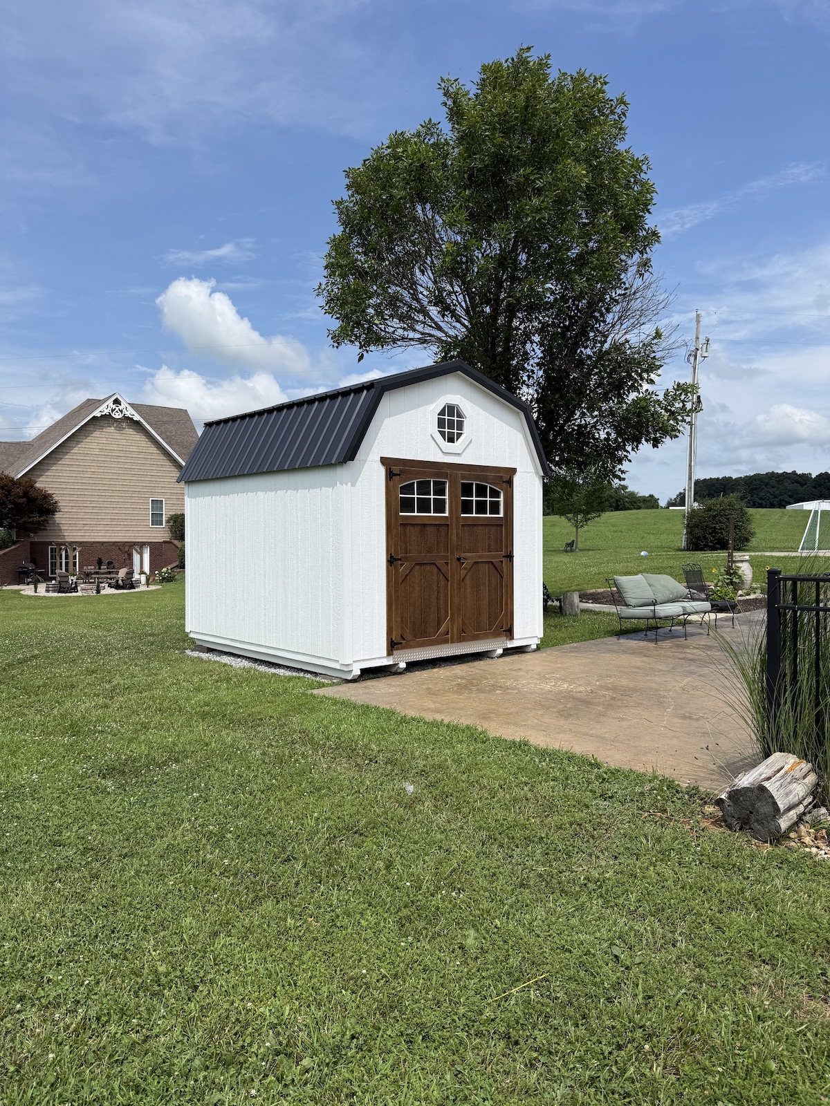 A white lofted barn shed delivered to a backyard patio