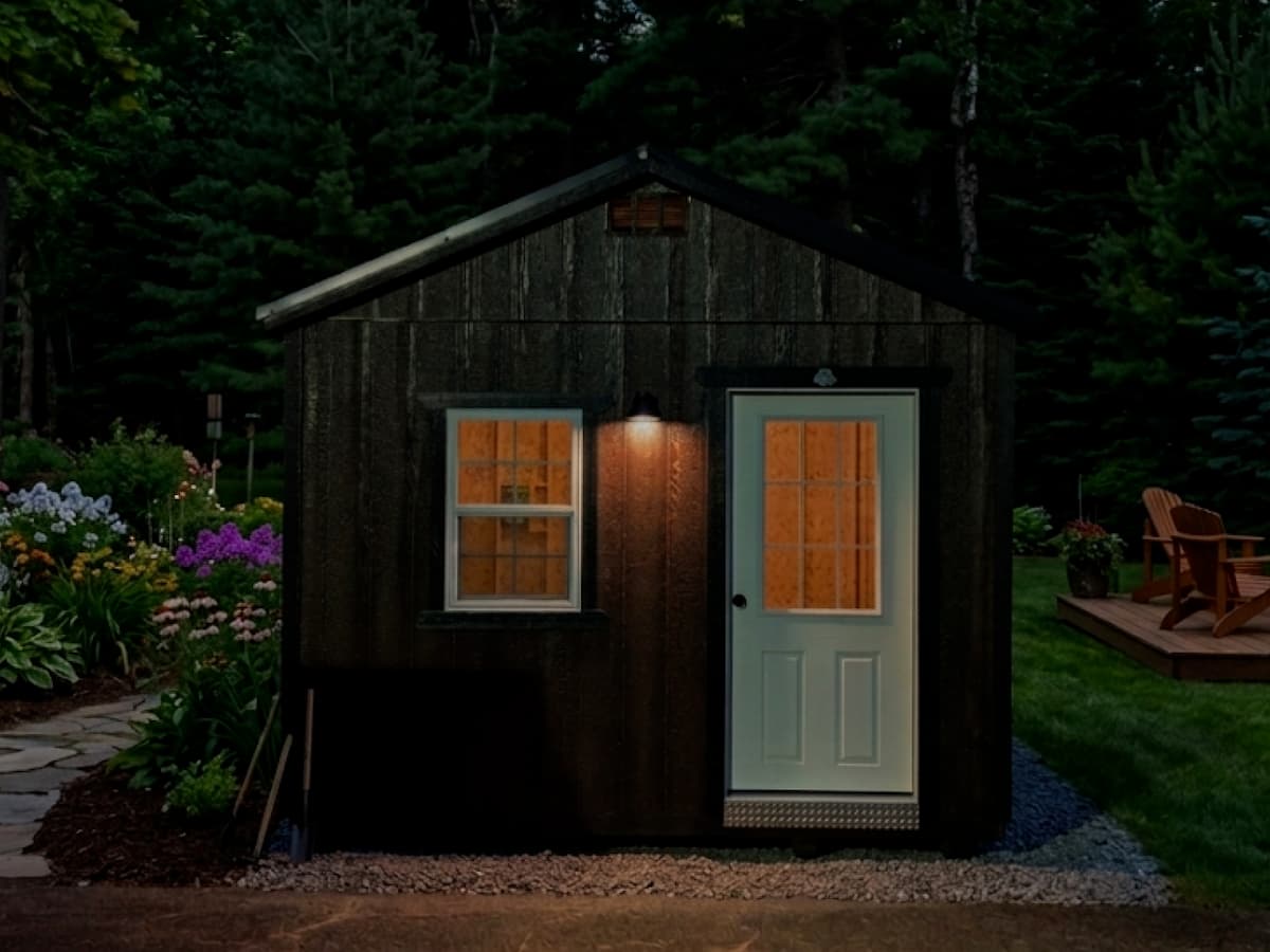 Dark stained Gable Shed at dusk with lit window and entry door